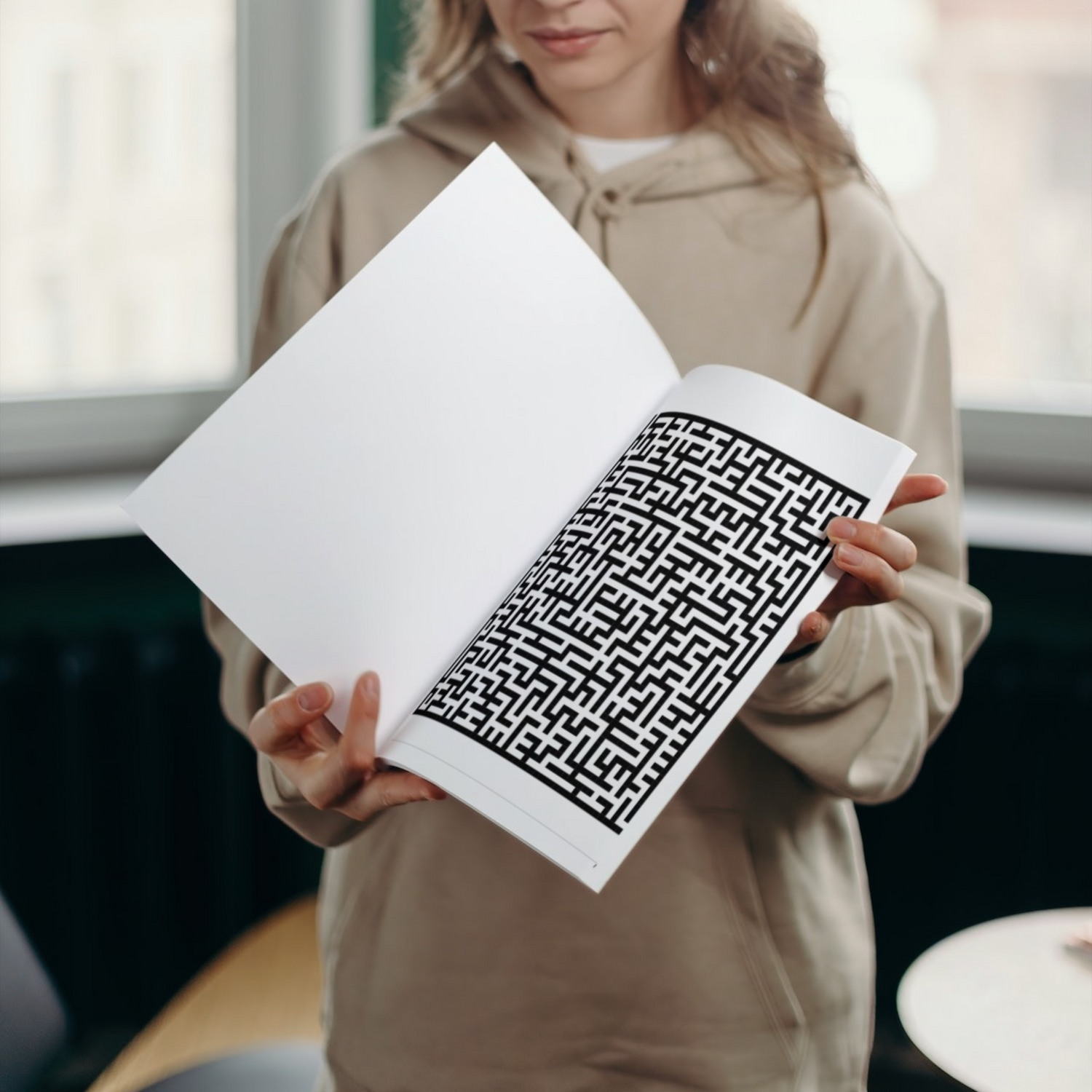 An interior page of "Halloween Maze Book for Kids 9-13" by ArisaTeam in the hands of a girl showing one of the mazes.