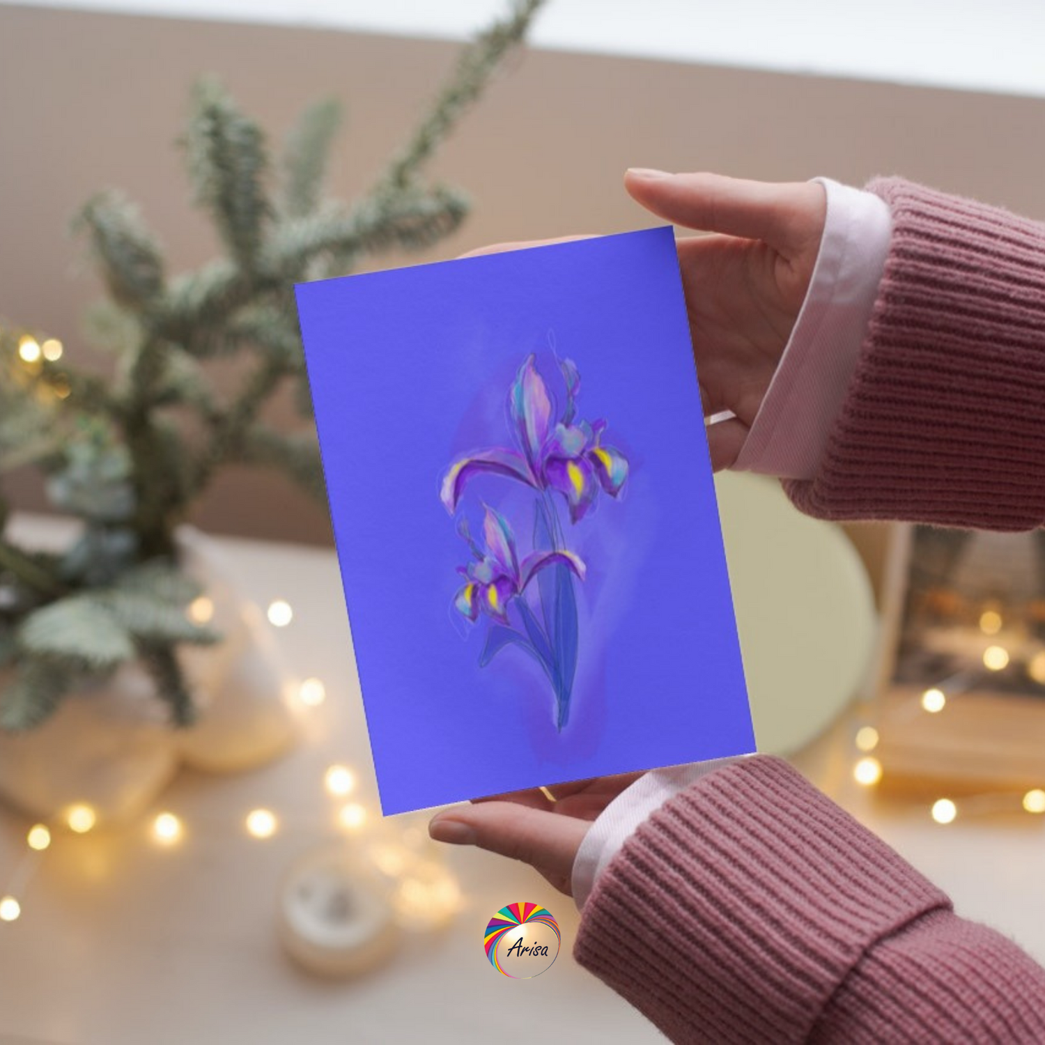 Person holding February Iris birth flower greeting card in a cozy holiday setting.