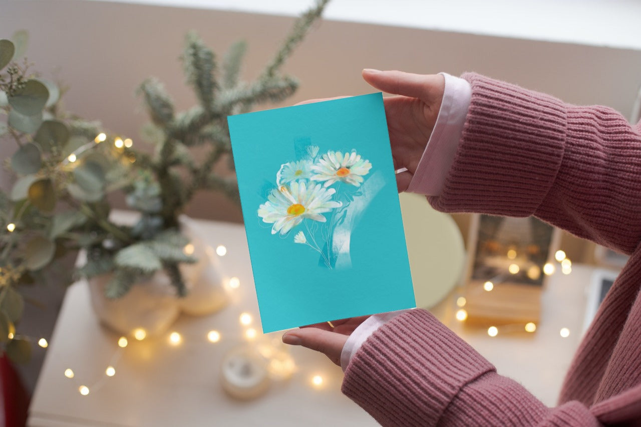 April daisy birth flower greeting card held in hand in a cozy setting