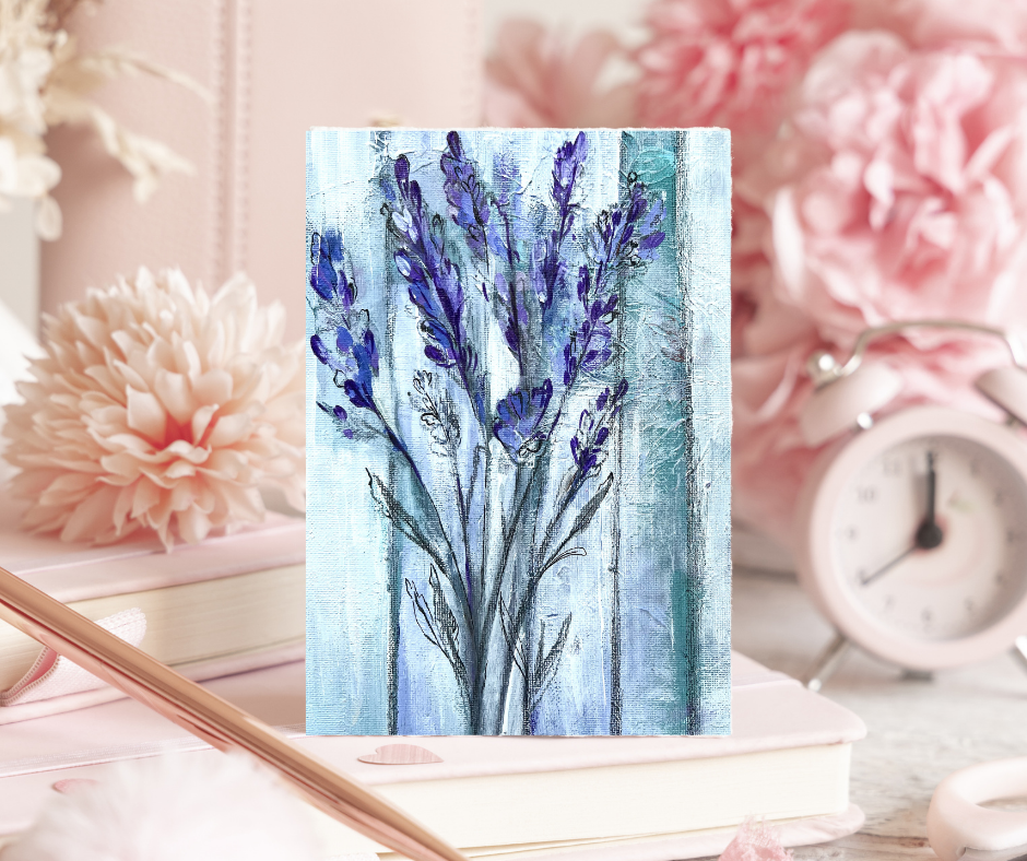 Ethereal lavender greeting card with soft abstract floral artwork displayed on a desk with books, flowers, and a clock in the background