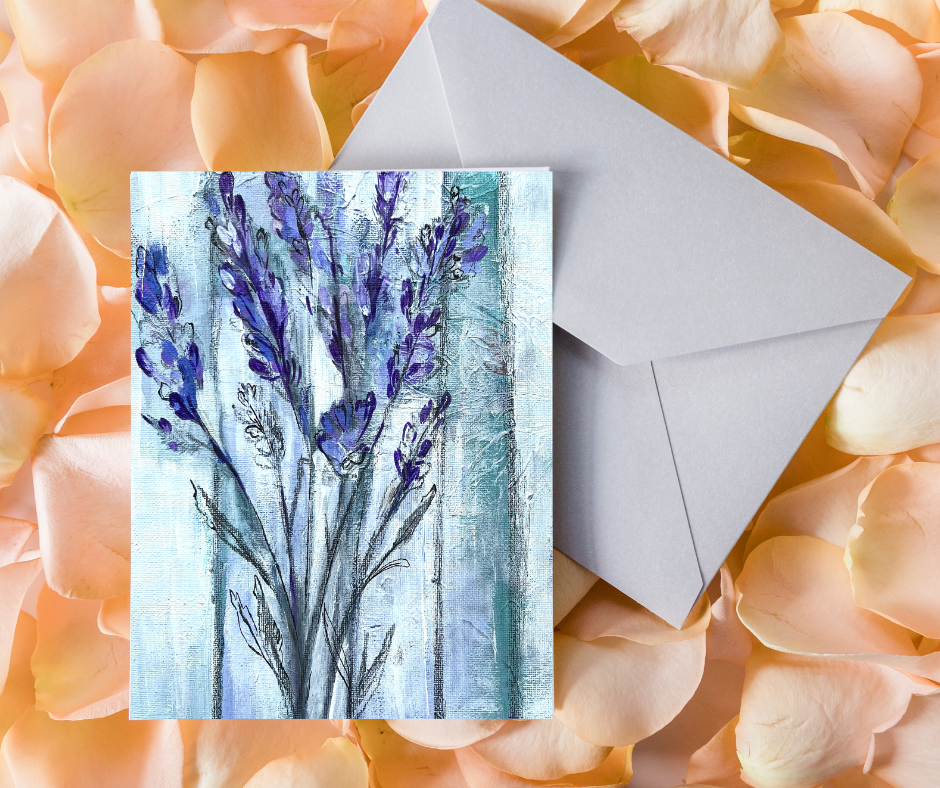 Ethereal lavender greeting card with soft abstract floral artwork displayed with an envelope on a bed of peach-colored flowers