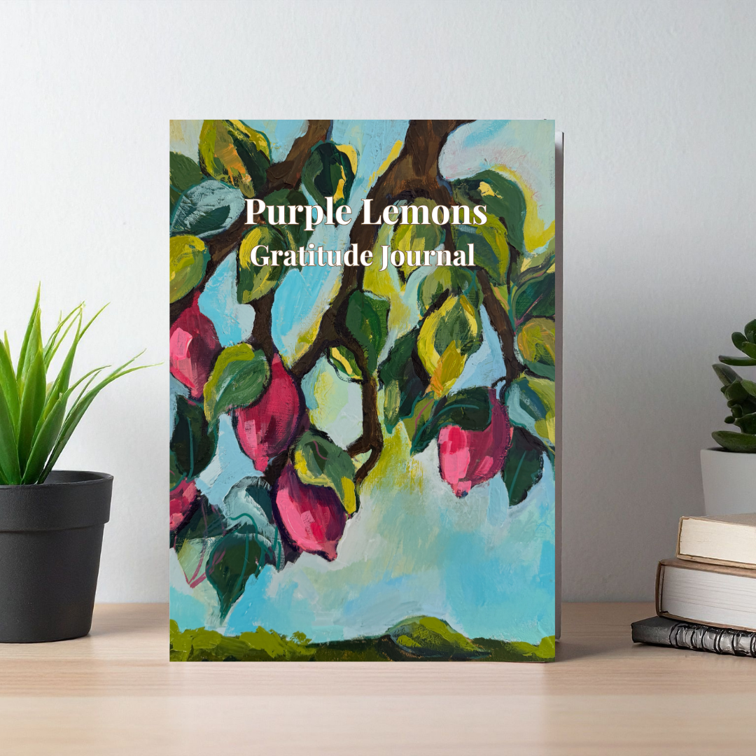 Purple Lemons gratitude journal with colorful lemon tree artwork cover displayed on a desk