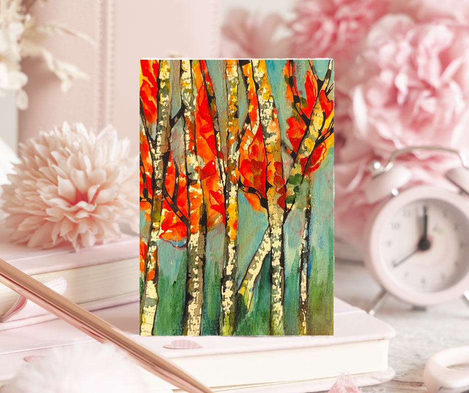 Whispers of Fall greeting card featuring vibrant autumn trees with orange and red leaves displayed on a desk with books, flowers, and a clock