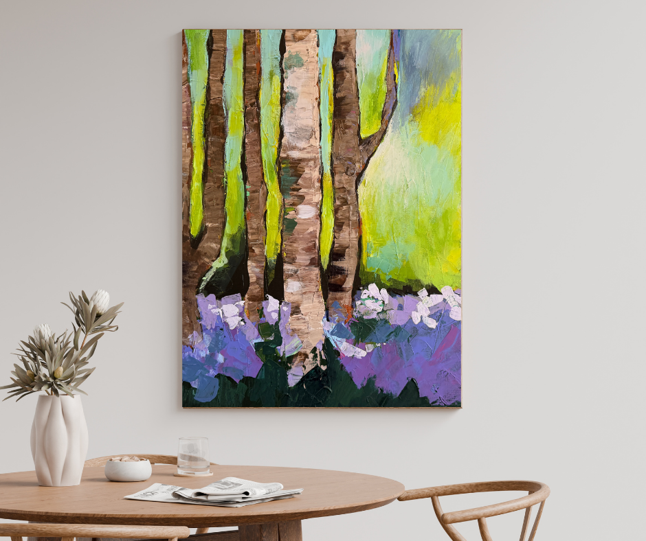 Green and purple forest canvas wall art displayed above a wooden table in a soft neutral dining space