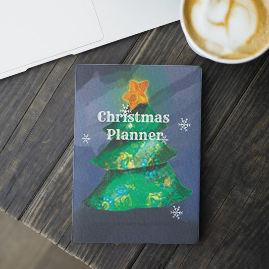 the tree Christmas planner by arisateam with a Christmas tree and a star on top of the tree in the cover design and close to a cup of coffee and a laptop