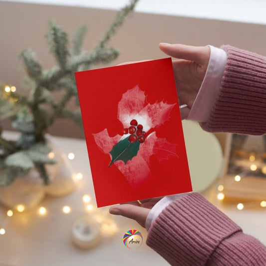 "Holly" Greeting Card by ArisaTeam in the hands of a woman and in a Christmas background ideal as a Christmas card.