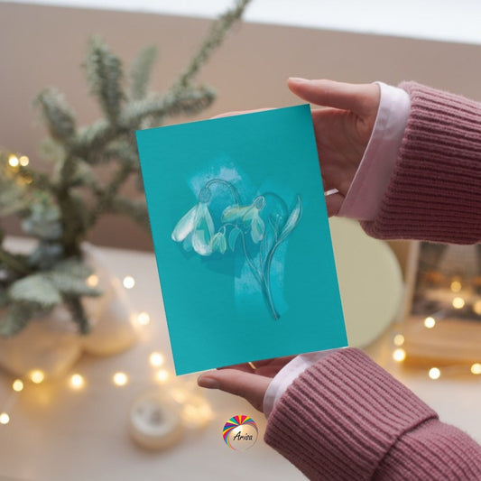 "SNOWDROP" Greeting Card by ArisaTeam in the hands of a woman and in a Christmas background ideal as a Christmas card.